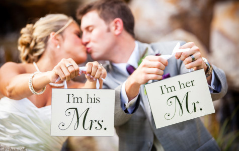 Bride and groom kissing and holding signs